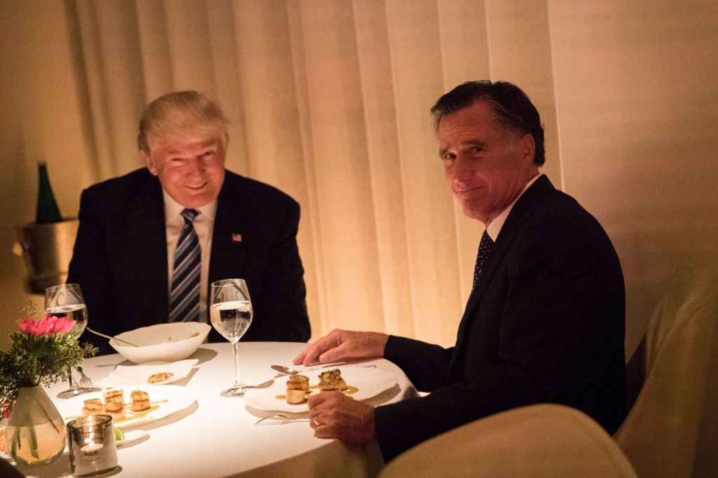 Donald Trump, asshole supreme, looks into the camera with a self-satisfied smile while having dinner with Mitt Romney in 2016. Mitt is at right, his head turned and gives the photographer a very sheepish look. 